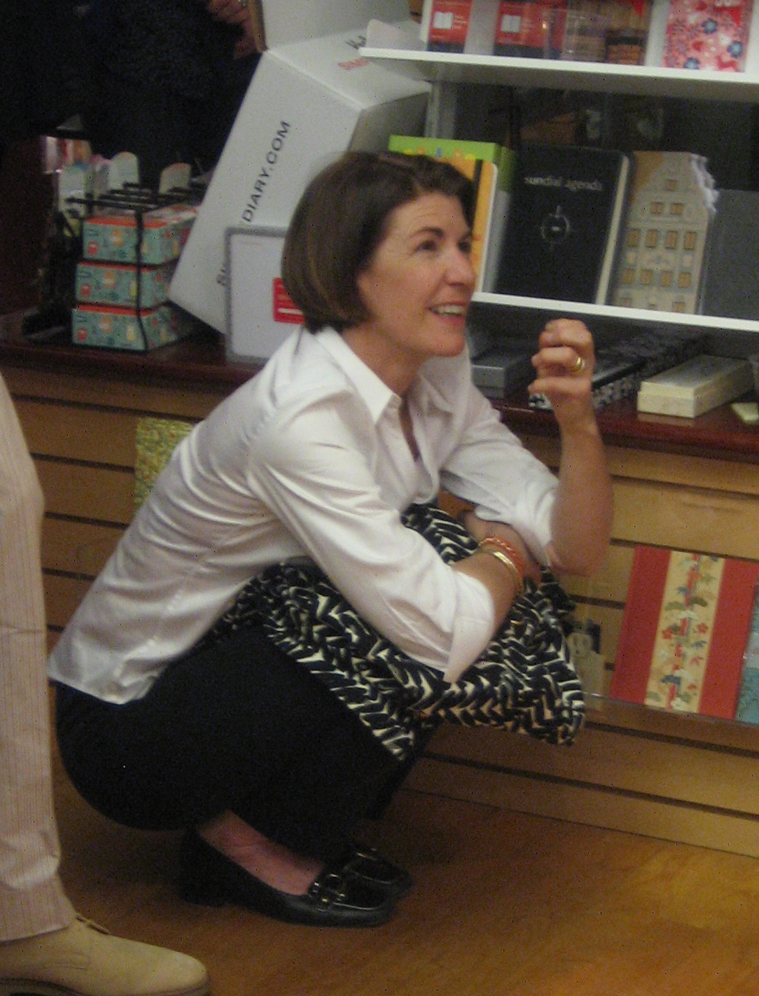 a woman kneeling down in front of shelves holding a bag