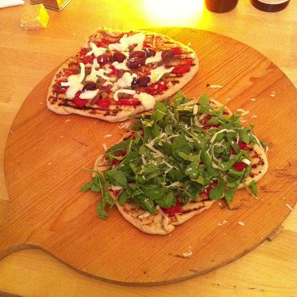 two pizzas sitting on top of a wooden  board