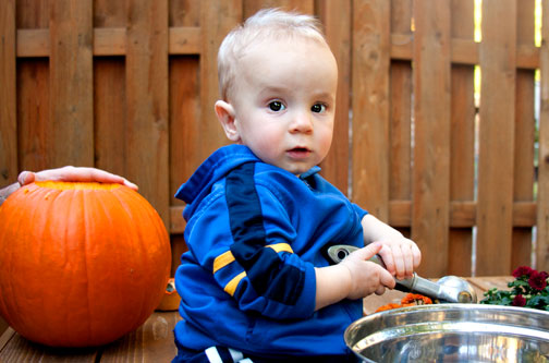 a baby sitting on a table in front of a bowl