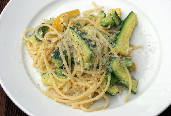 a plate of spaghetti and cucumbers with parmesan cheese
