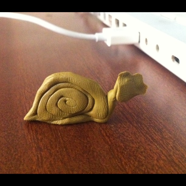 a snail is shown sitting on a table next to a plug in the wall