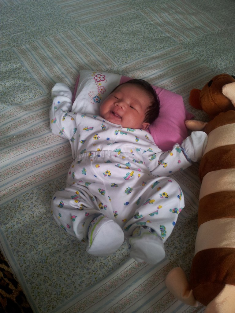 a newborn baby laying on it's side next to stuffed animals