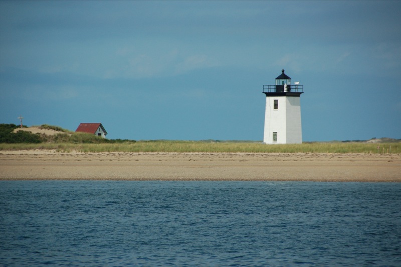 lighthouse overlooking the blue ocean in a wide open field