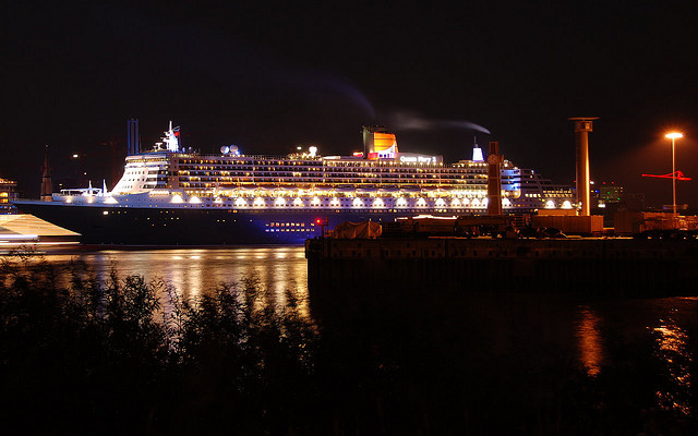 a ship sits docked at night as the lights shine on