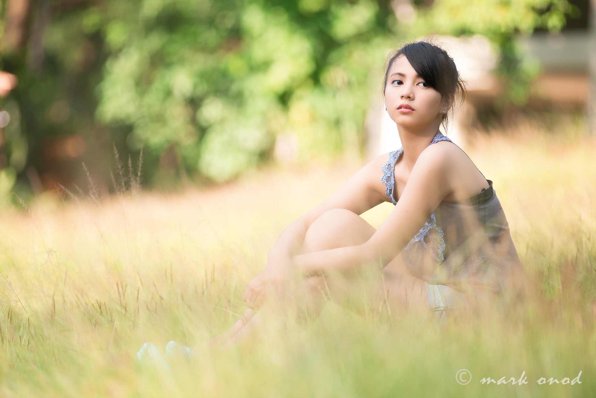 an asian woman posing for the camera in some tall grass