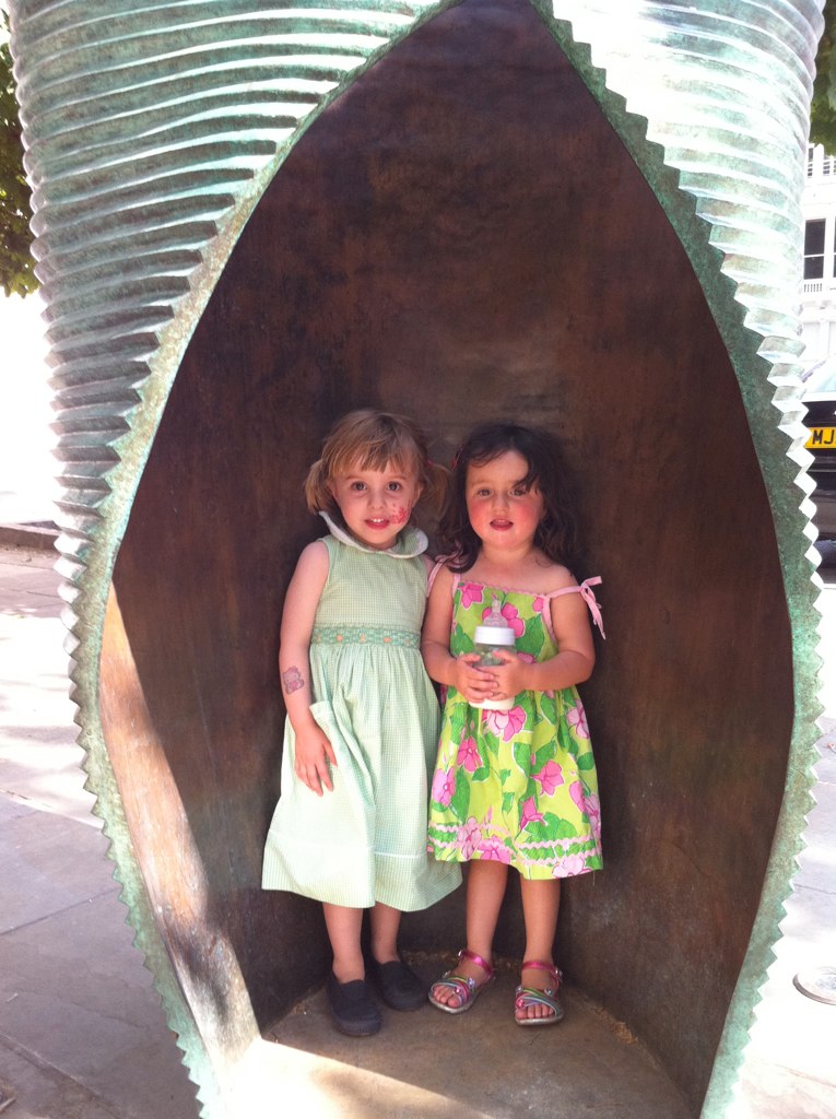 two girls standing in front of a sculpture