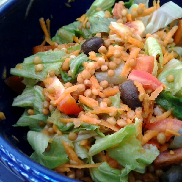 a salad in a bowl is shown with carrots, corn, lettuce and tomatoes