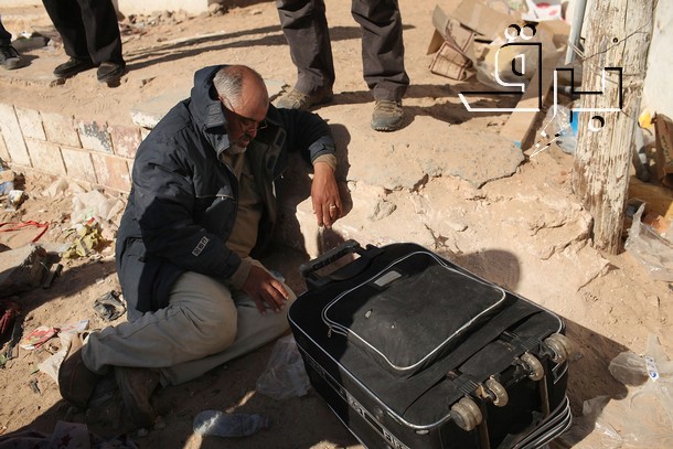 a man squatting down next to an open suitcase