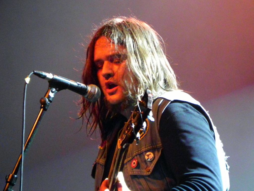 a man singing into a microphone while holding a guitar