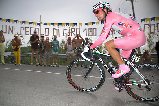 a bicyclist wearing a pink suit is racing on his bike