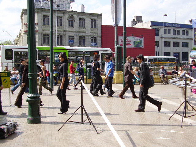 some people are standing around on the sidewalk and taking pictures