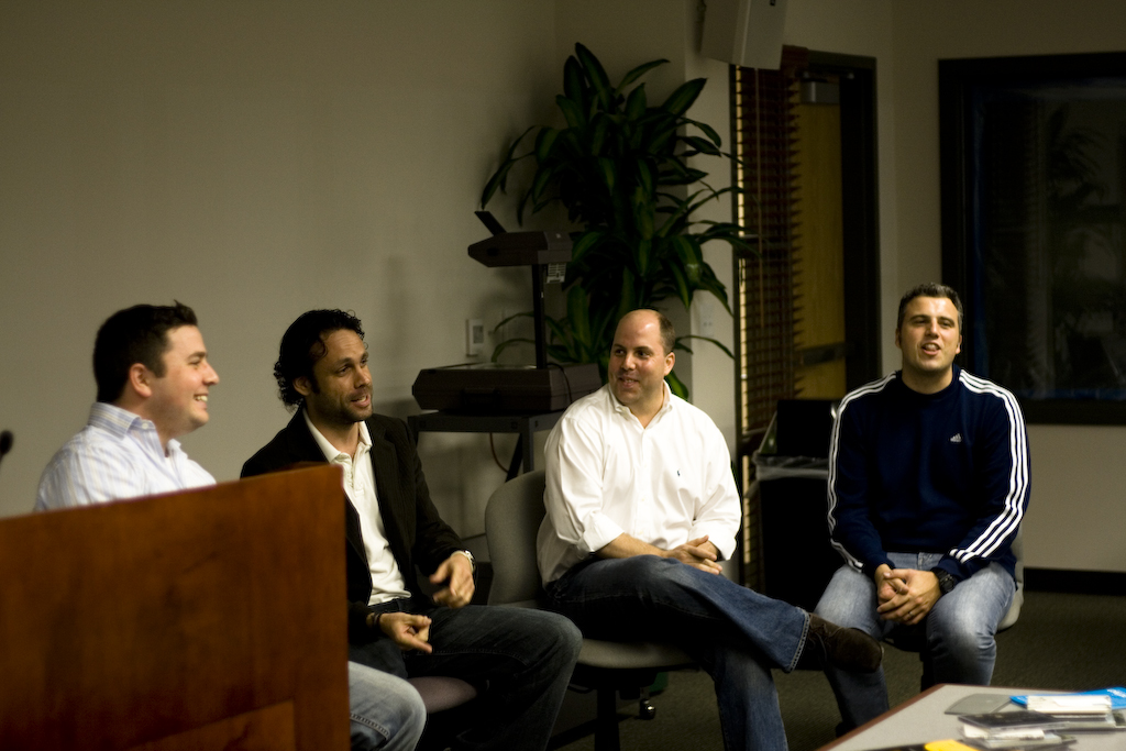 four people are sitting in a meeting room and smiling