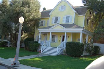 a yellow house with white stairs and green lawn