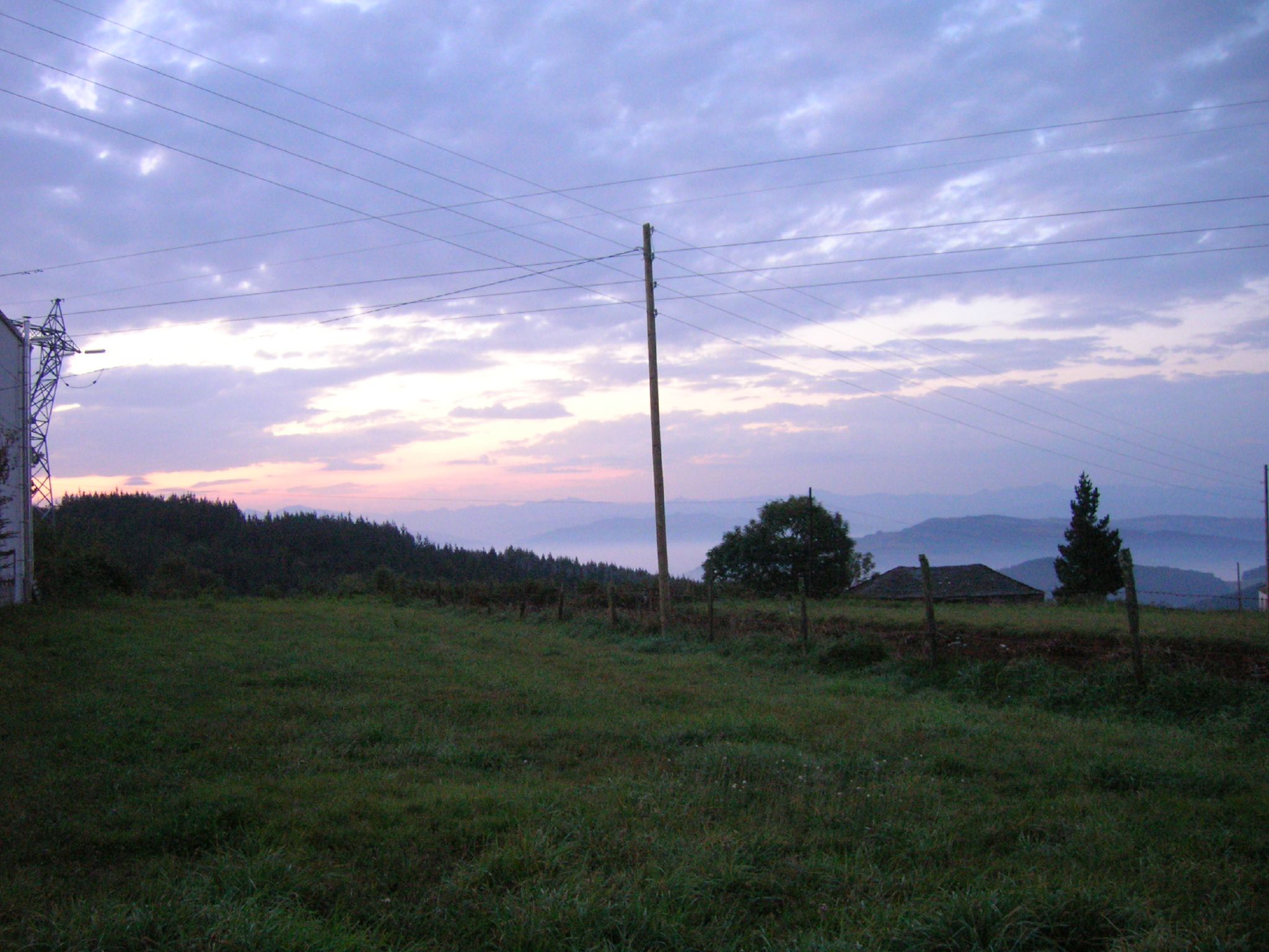 an empty field near a power pole on a hill