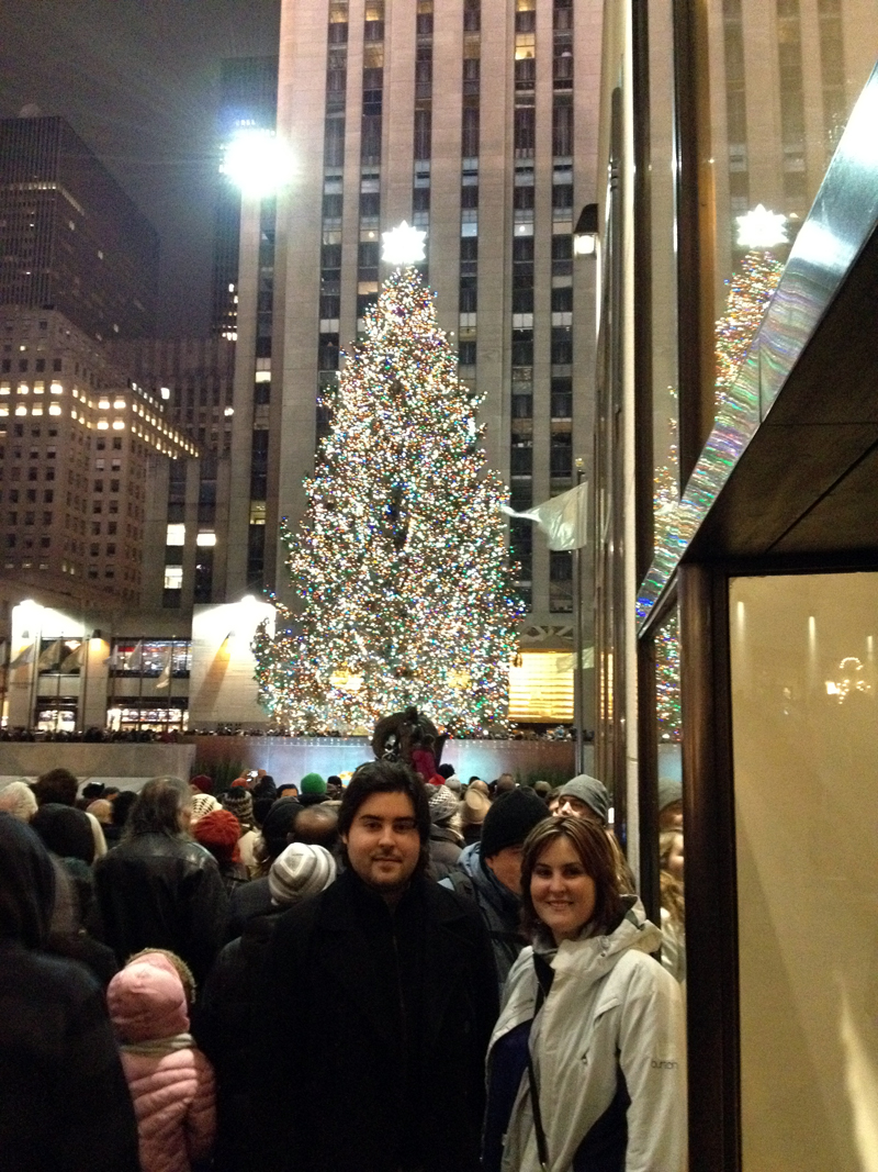 people standing in a crowd in front of a christmas tree