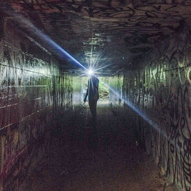 a man walking into a tunnel covered in graffiti