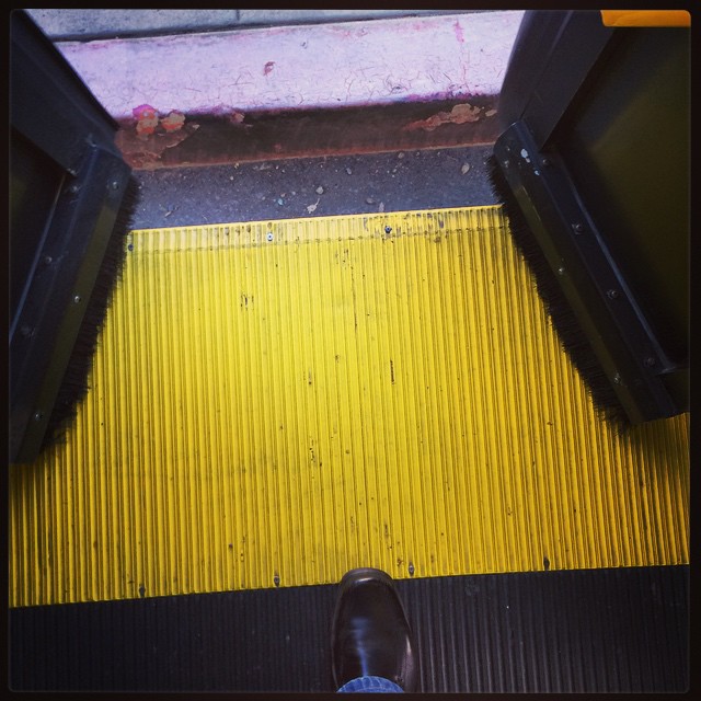 feet of someone standing on an outdoor yellow and black platform