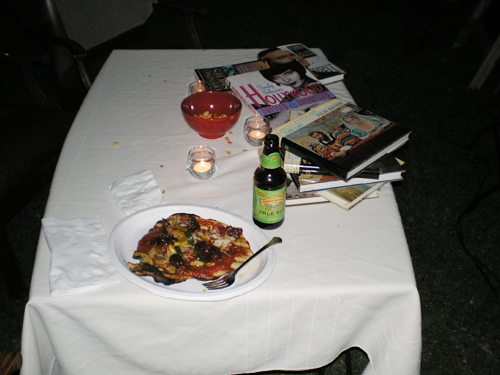 a table topped with a plate of pizza next to glasses of beer and other food