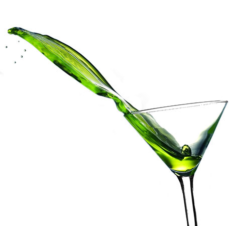 an olive colored liquid is poured into a martini glass