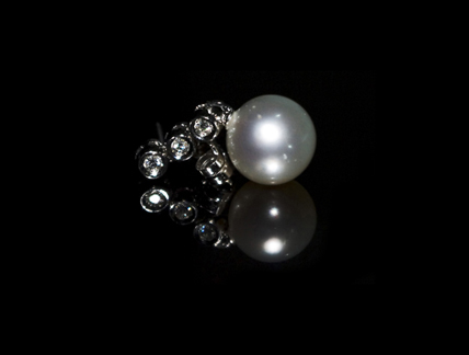 two pearls with some silver diamonds on a black surface