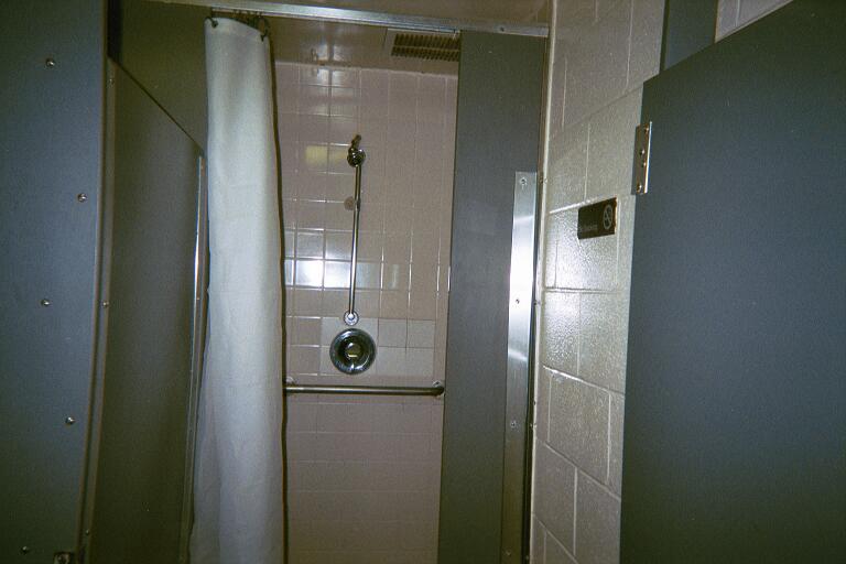 a walk in shower that has been decorated with white tiling and a brown tiled wall