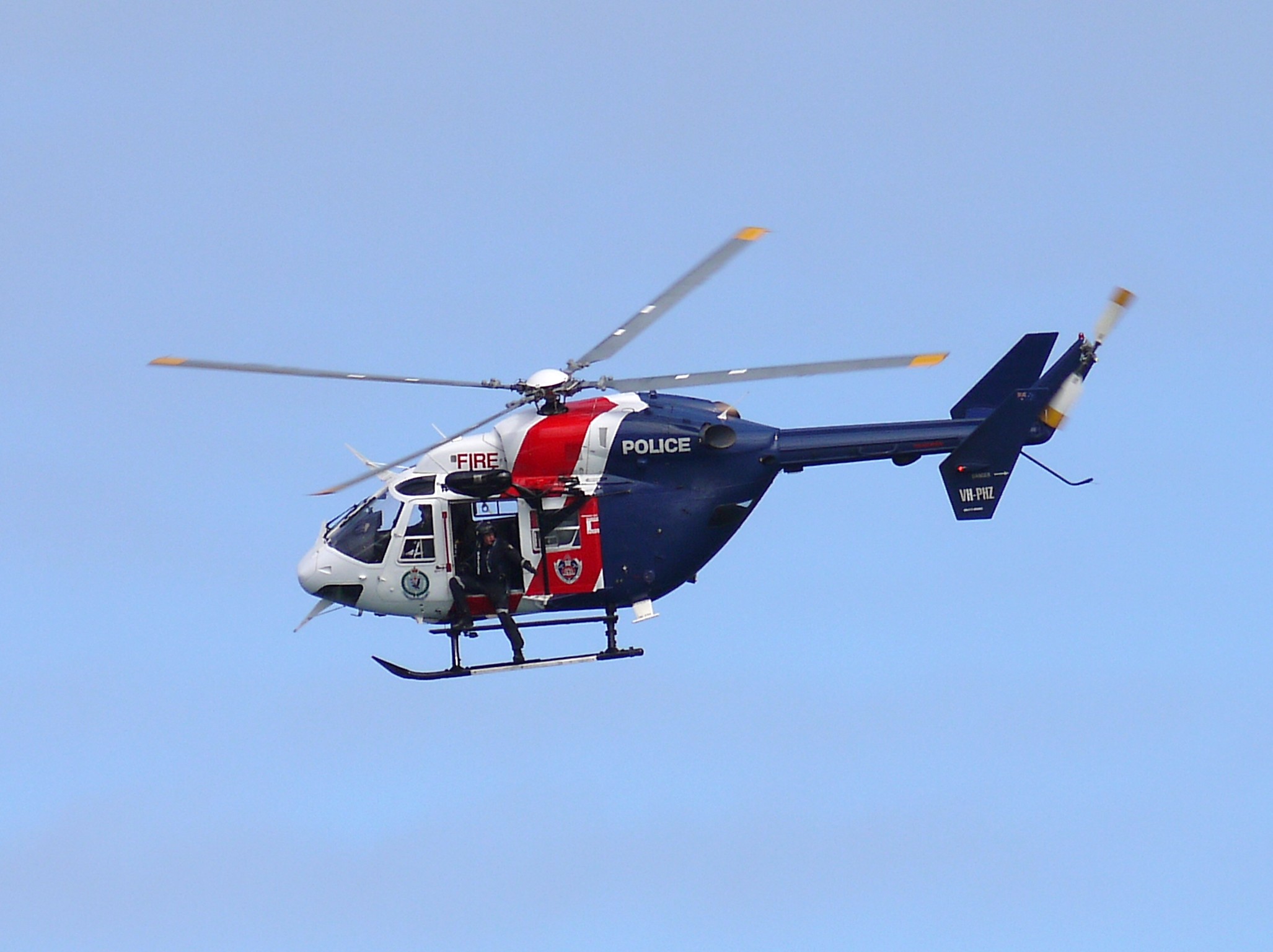 a red and blue helicopter flies in the air