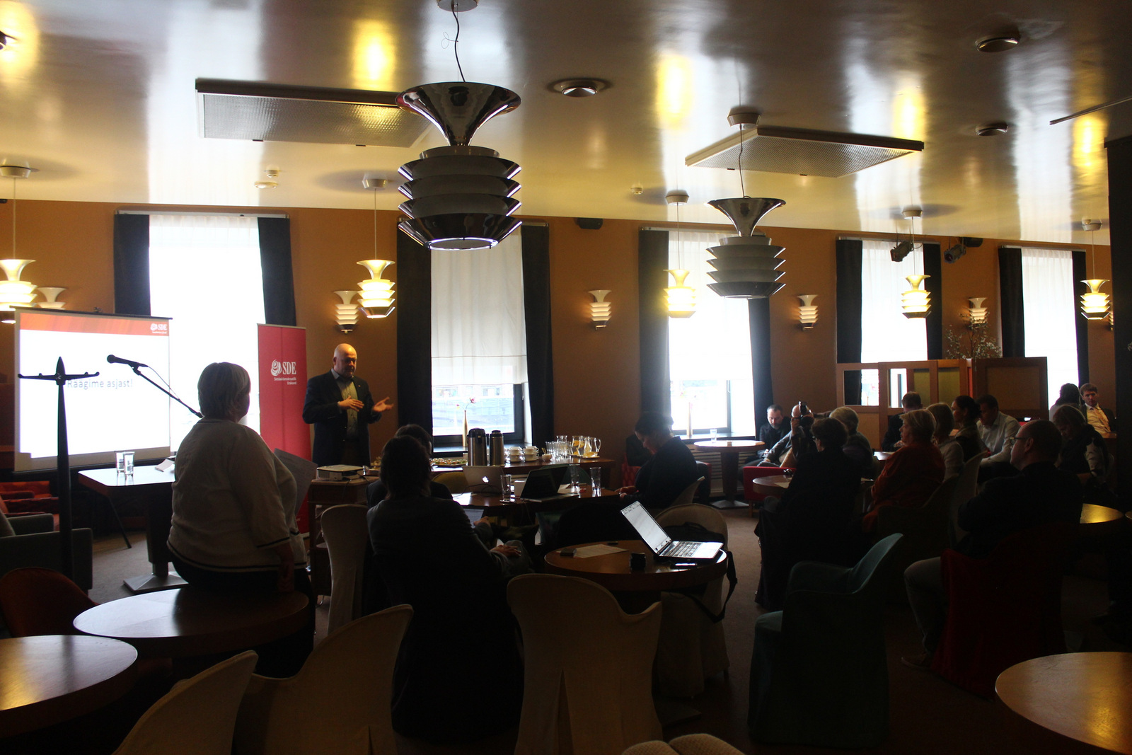 a crowd in a restaurant is in front of a speaker