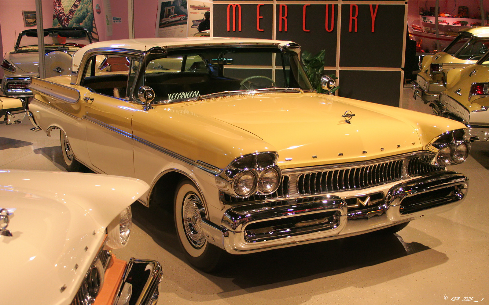 an antique yellow car is displayed in the center of a museum