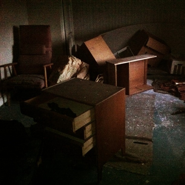 a desk and chair are strewn over with garbage in a dark room