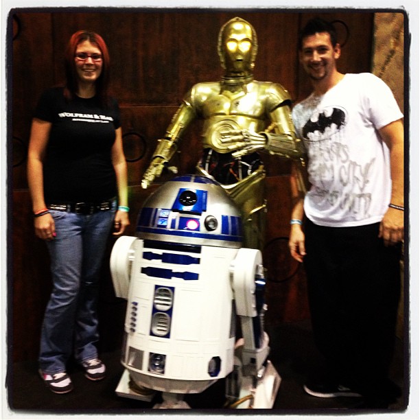 a man and a woman stand beside an elaborately decorated robot