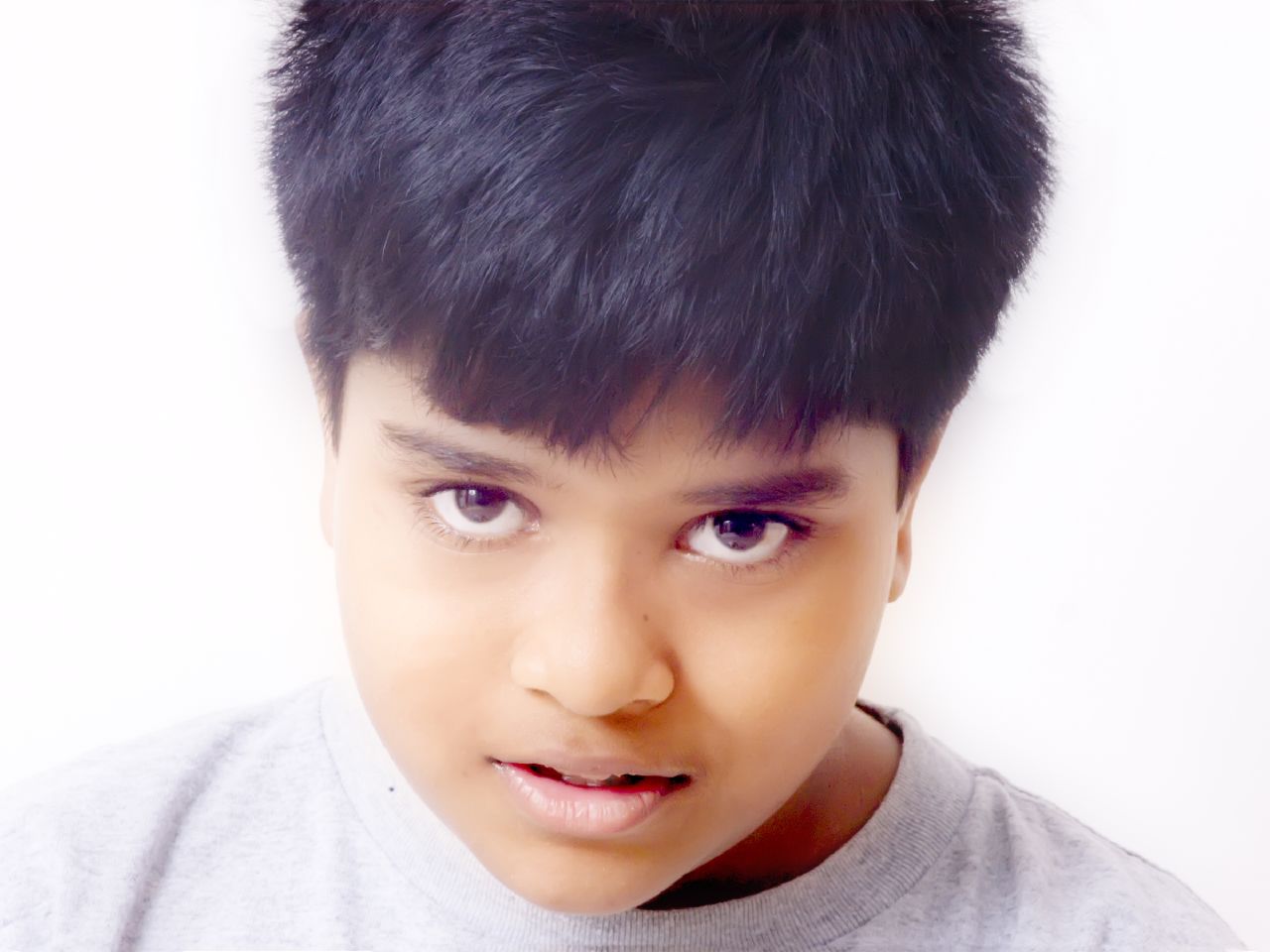 a boy with a short black hair is looking at the camera