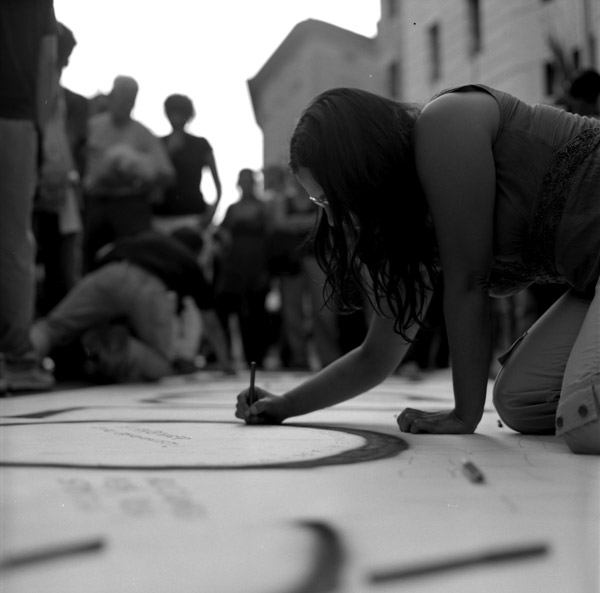 a woman bends down on the floor while drawing a circle