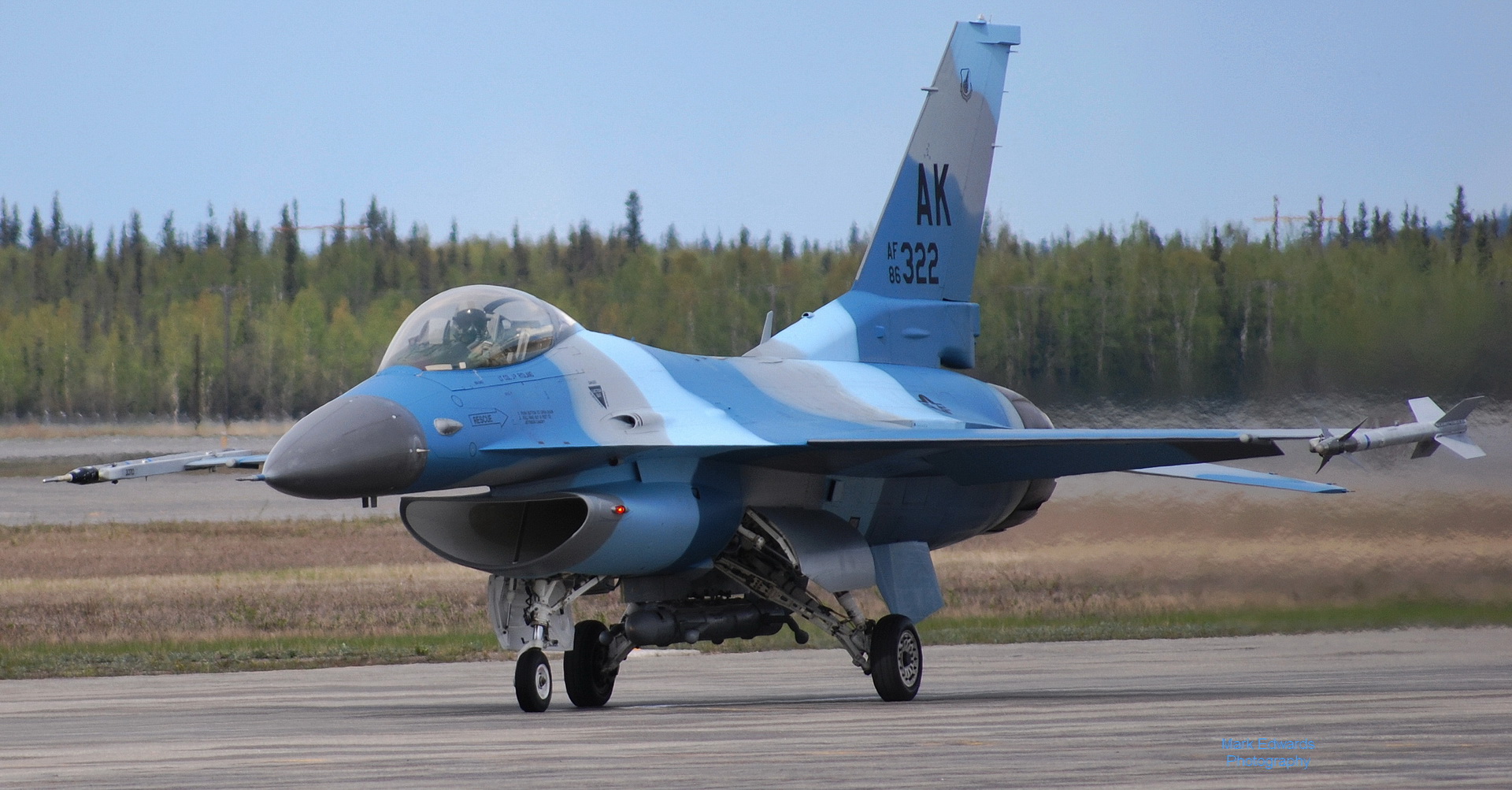 a blue jet airplane taking off from an airport runway