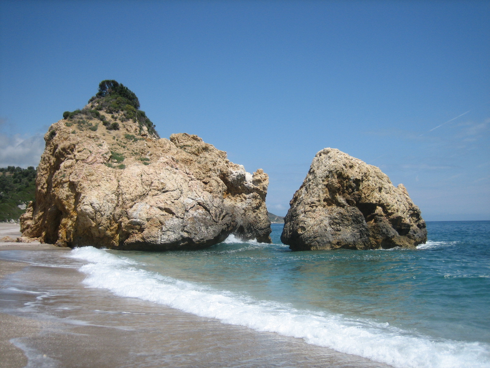 the beach has rock formations next to the water