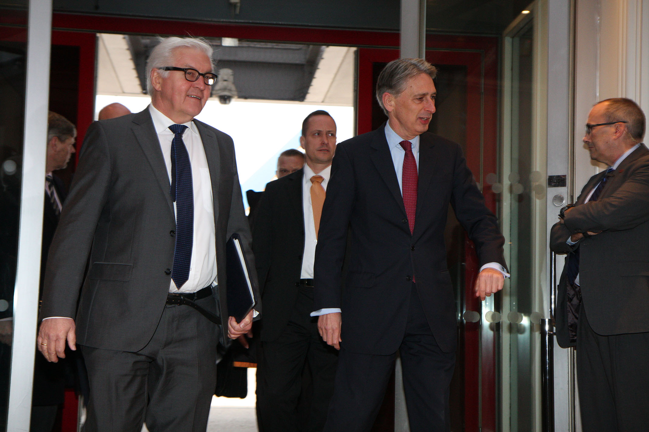 three men in business suits walking through a building