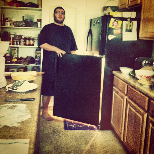 a man standing in the kitchen with his refrigerator broken