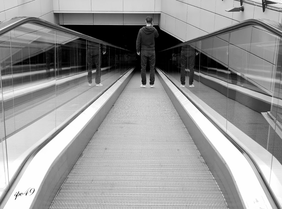 a black and white po of a person walking through an escalator
