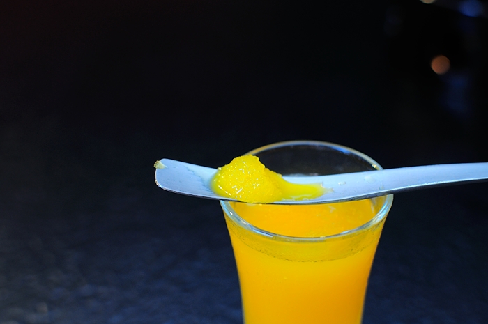 a glass of orange juice and a spoon in it