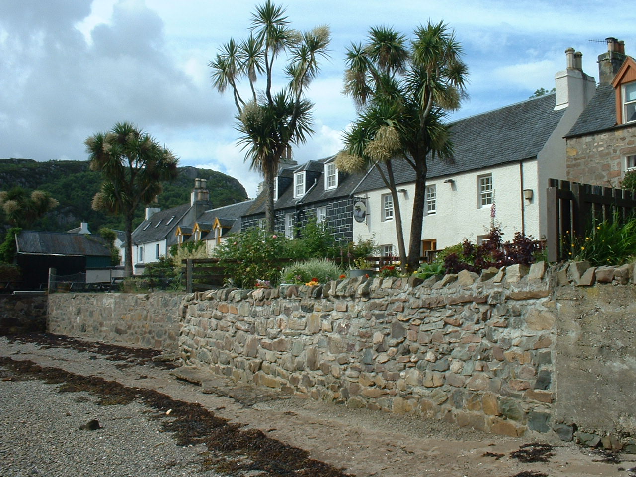 a stone wall and buildings on the shore