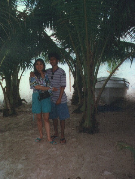 a man and woman standing next to each other in a tropical forest