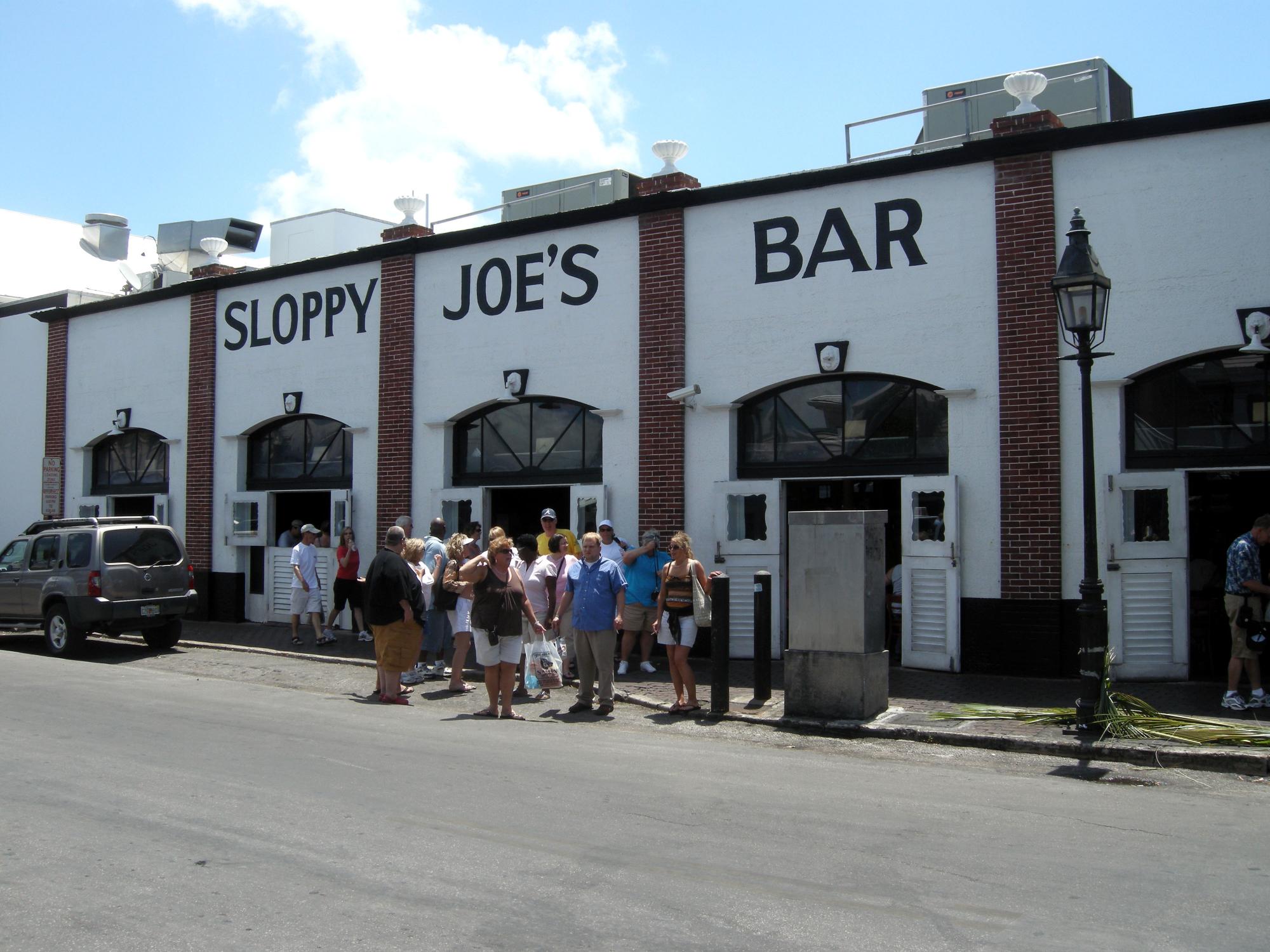 the people are outside of the bar by the street