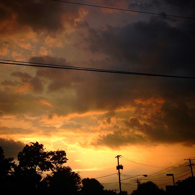 an orange sky with clouds and lines and power lines