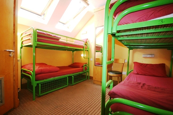 the room has a lot of bunk beds with red covers on them