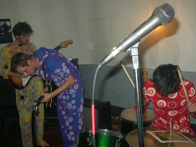 two men and a woman singing in front of a microphone