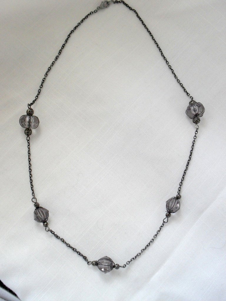black metal and glass necklace on white fabric