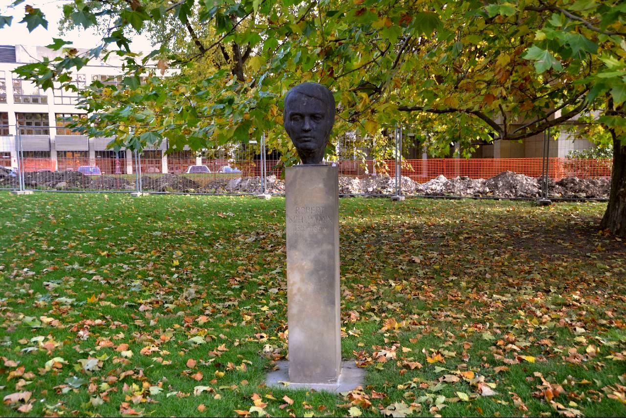 a bust of a man standing next to some trees
