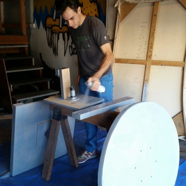 a man sanding a large disk next to a wooden table