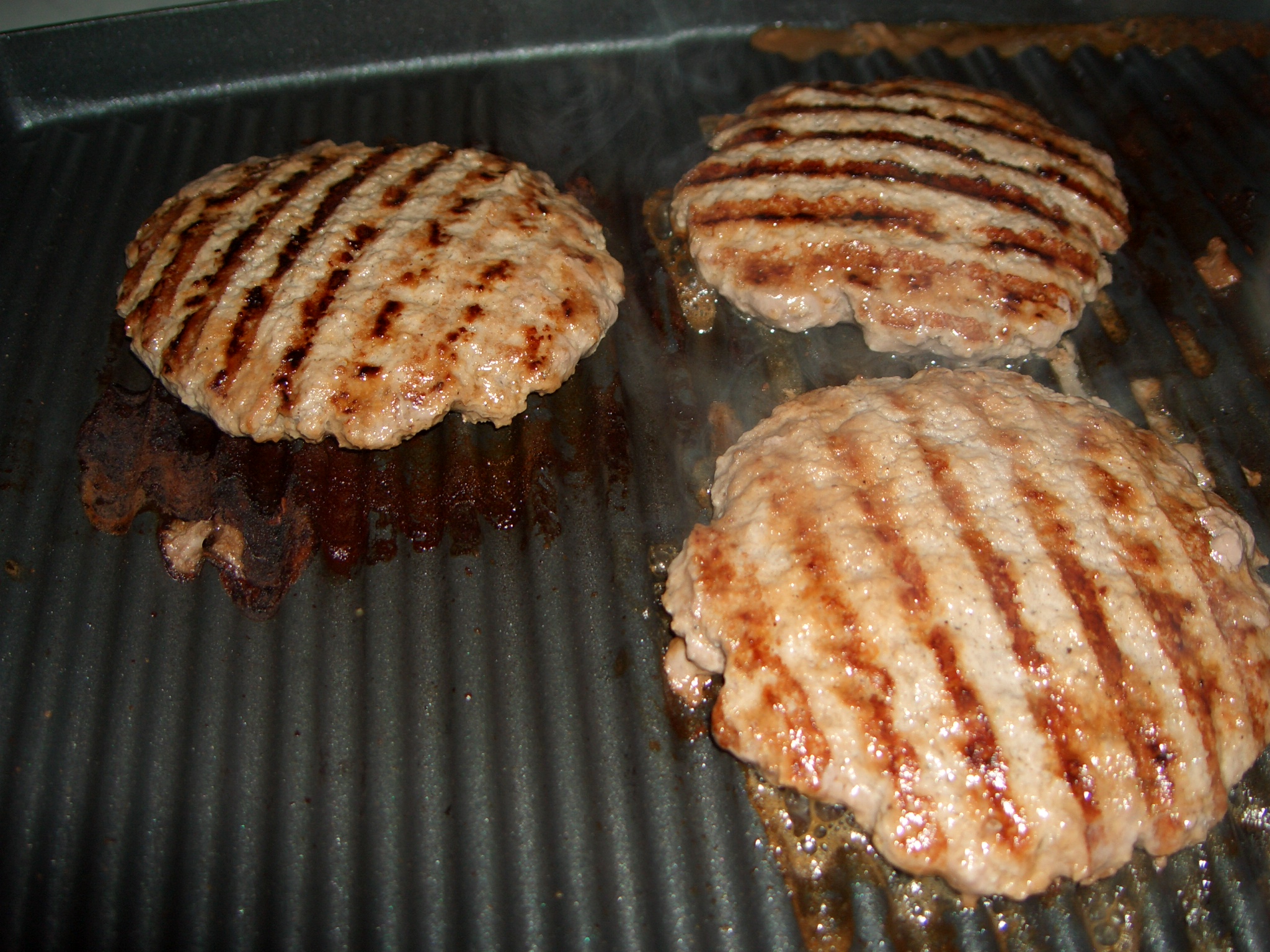 some burgers and a hamburger patty on a grill