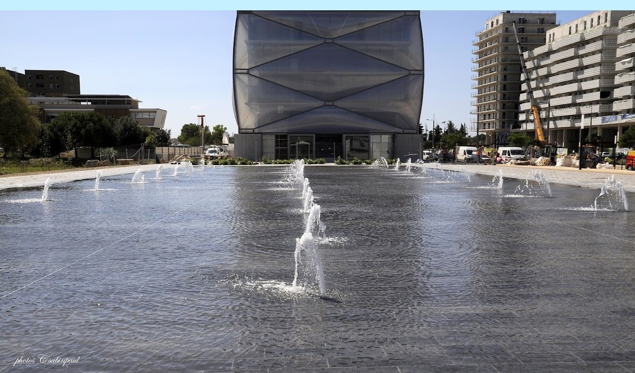 an elaborate public fountain surrounded by fountains with buildings in the background