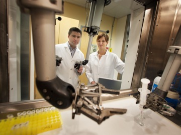 a scientist and a colleague standing in front of a microscope